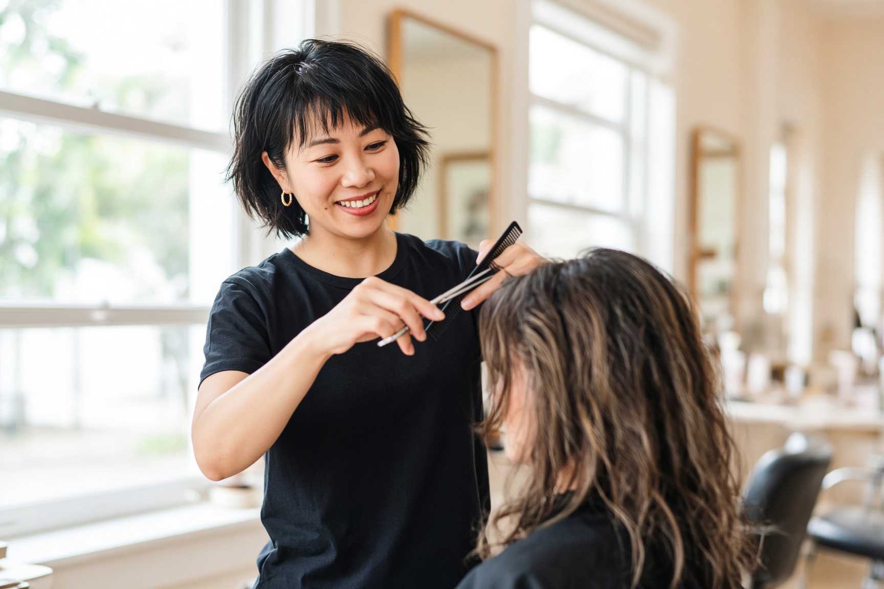A stylist cutting a client’s hair in a bright US salon.